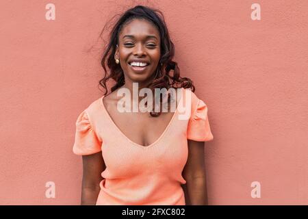Donna sorridente in abbigliamento casual a parete Foto Stock