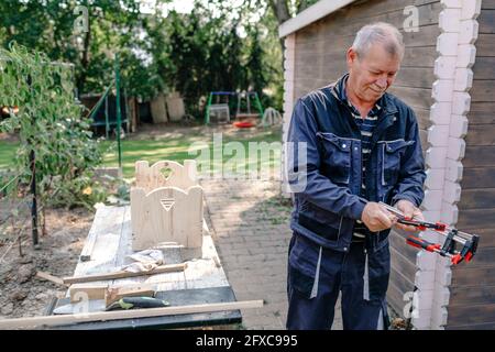 Uomo anziano che fa lavoro di Falegnameria nel cortile Foto Stock