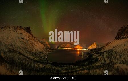 Norvegia, Tromso, Bergsbotn, veduta panoramica di Aurora Borealis sopra il villaggio illuminato fiordo sull'isola di Senja Foto Stock