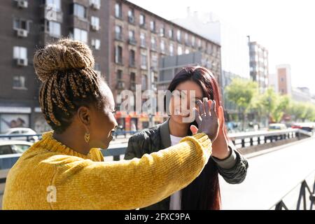 Amici femminili multietnici che si danno cinque persone l'una all'altra nella strada Foto Stock