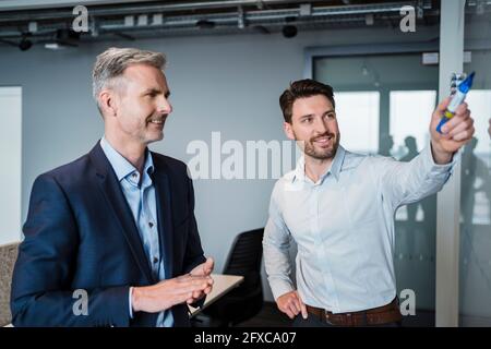 Sorridente gente di affari che discute sopra la lavagna in riunione al posto di lavoro Foto Stock