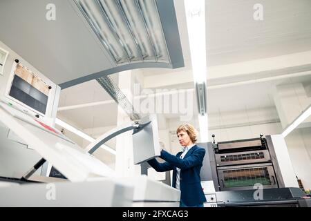 Esperienza femminile nell'uso della macchina da stampa in officina Foto Stock