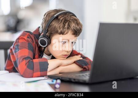 Ragazzo che frequenta le lezioni online con il laptop mentre e-learning a casa Foto Stock