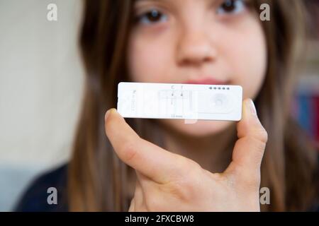 Ragazza che tiene un test diagnostico rapido a casa mostrando un risultato negativo Foto Stock