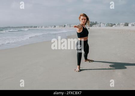 Bella donna che pratica yoga in spiaggia durante la giornata di sole Foto Stock