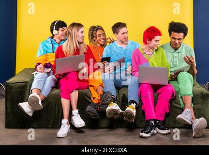 Amici millenari che studiano insieme mentre si siedono sul divano in studio Foto Stock