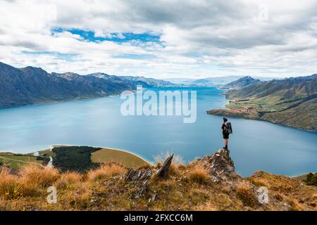 Nuova Zelanda, Otago, escursionista di Male ammirando la vista del lago Hawea dalla cima della montagna Foto Stock