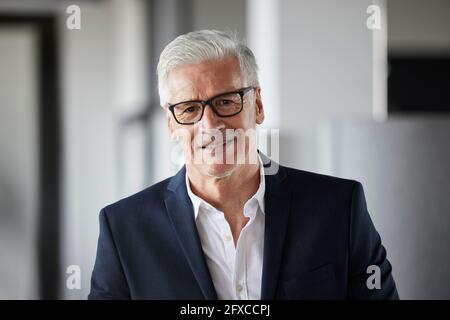 Imprenditore maturo che indossa occhiali sorridenti in ufficio Foto Stock