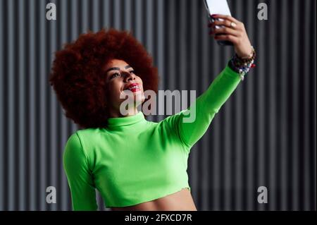 Donna sorridente che prende selfie sul cellulare Foto Stock