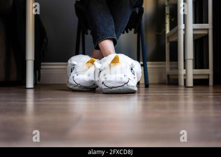 Donna che indossa morbide pantofole con gambe incrociate alla caviglia a casa Foto Stock