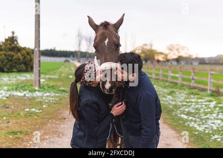 Uomo e donna baciano il cavallo sul sentiero Foto Stock