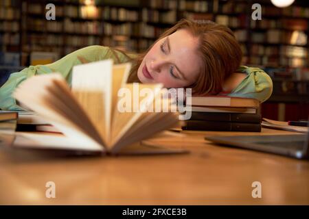 Donna stanca che dorme in biblioteca Foto Stock