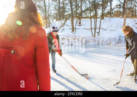 Uomo che gioca a hockey su ghiaccio con gli amici sulla neve Foto Stock