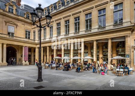 Parigi, Francia - 25 maggio 2021: Giorno dopo il blocco a causa della covid-19 in un famoso caffè parigino. I camerieri indossano maschere chirurgiche Foto Stock