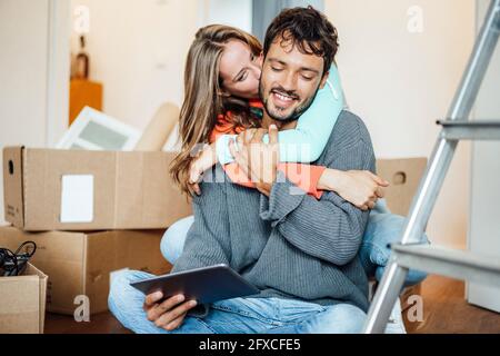 Giovane donna che baciava il ragazzo utilizzando un tablet digitale a casa Foto Stock