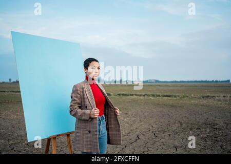 Donna in giacca in piedi di fronte alla pittura sul campo Foto Stock