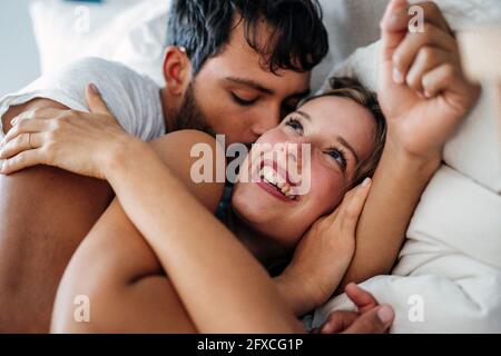 Giovane coppia romantica sdraiata sul letto a casa Foto Stock