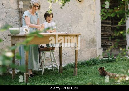 Donna matura con il nipote impastare l'impasto nel cortile posteriore Foto Stock