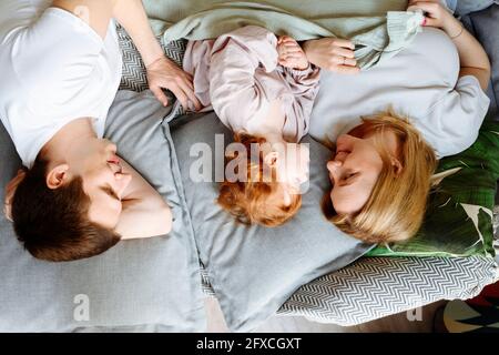 Famiglia giacente sul letto di casa Foto Stock