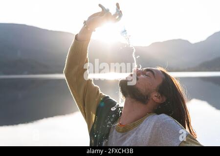 L'uomo versa acqua sul viso durante il giorno di sole Foto Stock