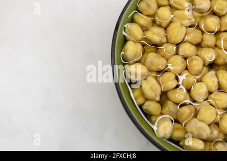 Ceci imbevuti in acqua, in ciotola, su tavola di marmo. Concetto di alimentazione sana, veganismo, vegetarianismo, sostituzione di carne e uova. Preparare i ceci b Foto Stock