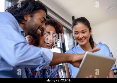 Sorridendo ai giovani colleghi che usano il tablet digitale all'università Foto Stock