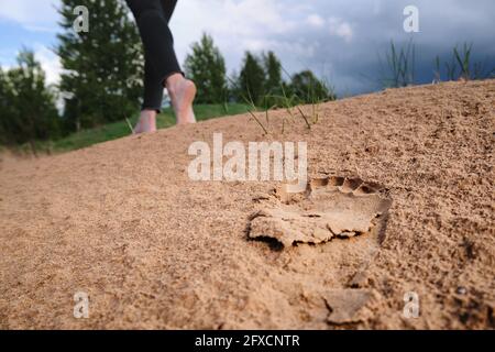 donna cammina a piedi nudi sulla sabbia. impronta nella sabbia. Foto Stock