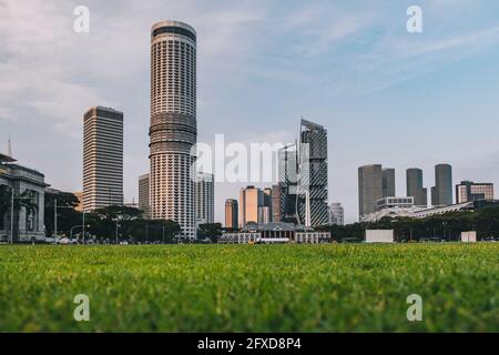 Padang gioca campi verdi con un angolo basso del centro congressi della città e altri grattacieli, Singapore. Foto Stock