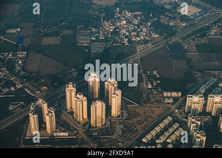 Edifici alti alla periferia di Kathmandu e la strada principale contro i campi verdi durante l'alba, mentre atterrano all'aeroporto internazionale, Nepal Foto Stock