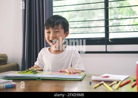 Ragazzo felice quando reding un libro di immagini a casa. Foto Stock