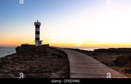 Passerella in legno in primo piano in direzione del faro di Maiorca Foto Stock