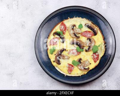 Omelette con champagne, formaggio e salsicce su un piatto rotondo su fondo grigio chiaro. Vista dall'alto, disposizione piatta Foto Stock