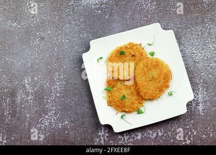 Hash browns su un piatto rotondo bianco su uno sfondo grigio chiaro. Vista dall'alto, disposizione piatta Foto Stock