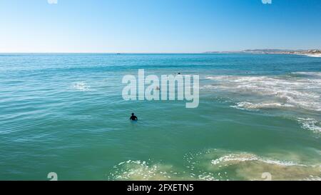 Low Altitude Shot in Oceano con Surfers tra Onde Foto Stock