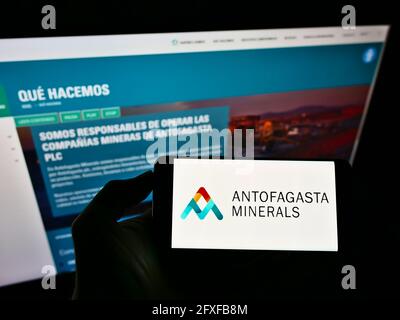 Persona che detiene il cellulare con il logo aziendale della società mineraria Antofagasta Minerals S.A. sullo schermo davanti alla pagina web. Mettere a fuoco il display del telefono. Foto Stock