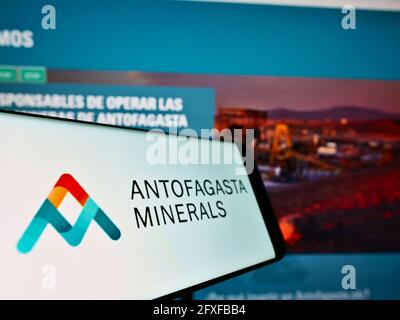 Cellulare con logo commerciale della società mineraria Antofagasta Minerals S.A. sullo schermo davanti alla pagina web. Mettere a fuoco il centro del display del telefono. Foto Stock