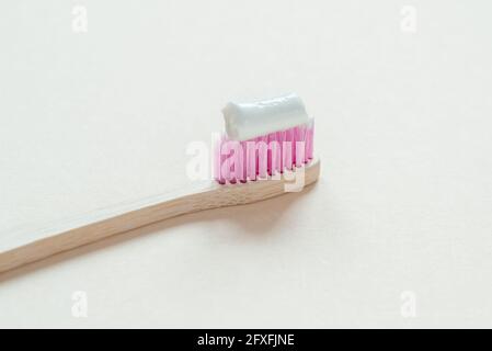 Spazzolino in bambù rosa con pasta dentaria su di esso primo piano, cura dentale con concetto zero rifiuti, stile di vita sostenibile Foto Stock