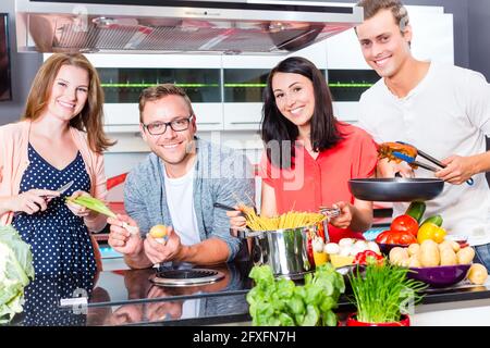 Amici cucinare gli spaghetti e carne in cucina domestica Foto Stock