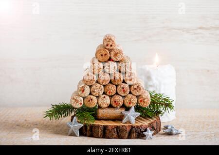 Decorazione creativa fatta a mano dell'albero di Natale fatta con i tappi della bottiglia del vino. Candela bianca che brucia su sfondo di legno, molto spazio di copia. Passaggio alla categoria superiore. Foto Stock