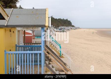 Una lunga linea di capanne si estende lungo il fronte mare a Wells-Next-Sea a Norfolk. Foto Stock