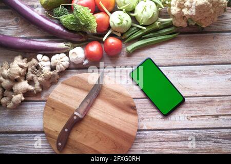 verdure fresche, tagliere e smartphone sul tavolo Foto Stock