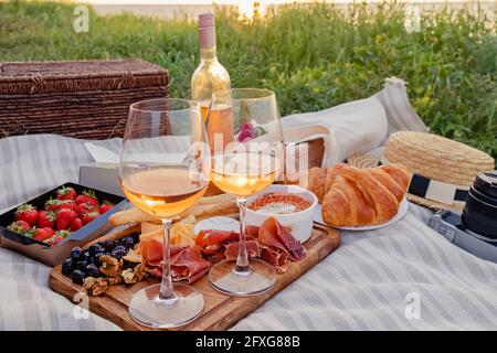 Picnic con fragole, croissant e antipasti a bordo e vino rosato. Foto Stock