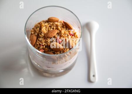 Foto di dieta yogurt con muesli e frutta secca, yogurt con cereali e mandorle, sano concetto di colazione con focus selettivo Foto Stock