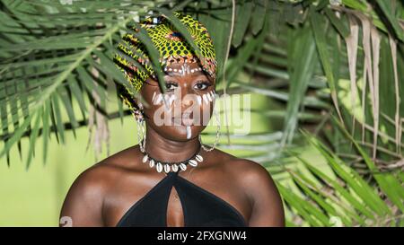 Donna africana nella giungla con il sole naturale della sera nella parte tropicale di Aburi Ghana Africa occidentale. Verniciato con il colore del tronco sul viso e sul tip Foto Stock