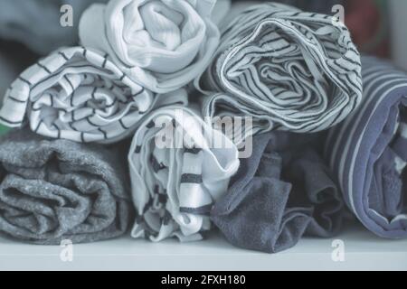 Marie Kondo tyding up metodo concetto - vestiti piegati. T-shirt bianche, grigie, blu e a righe. Messa a fuoco selettiva, immagine a toni Foto Stock