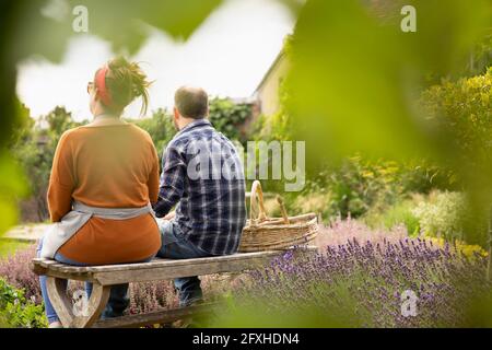 Coppia che prende una pausa dal giardinaggio nel cortile estivo soleggiato Foto Stock