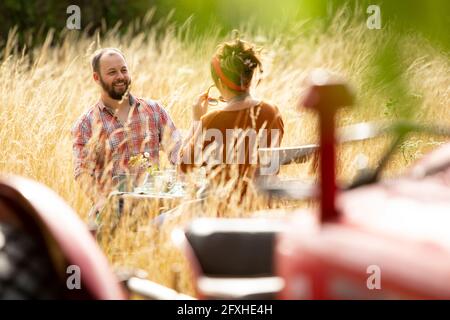 Felice coppia al tavolo dietro il trattore in estate soleggiato erba alta Foto Stock