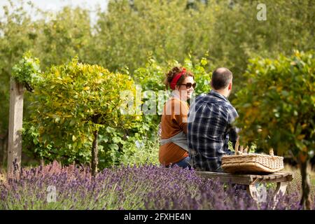 Coppia che prende una pausa dal giardinaggio nel giardino estivo soleggiato Foto Stock