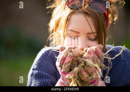 Primo piano donna che odora patate fresche raccolte Foto Stock