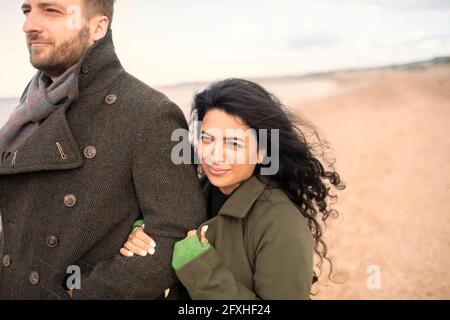 Felice coppia in cappotti invernali sulla spiaggia Foto Stock